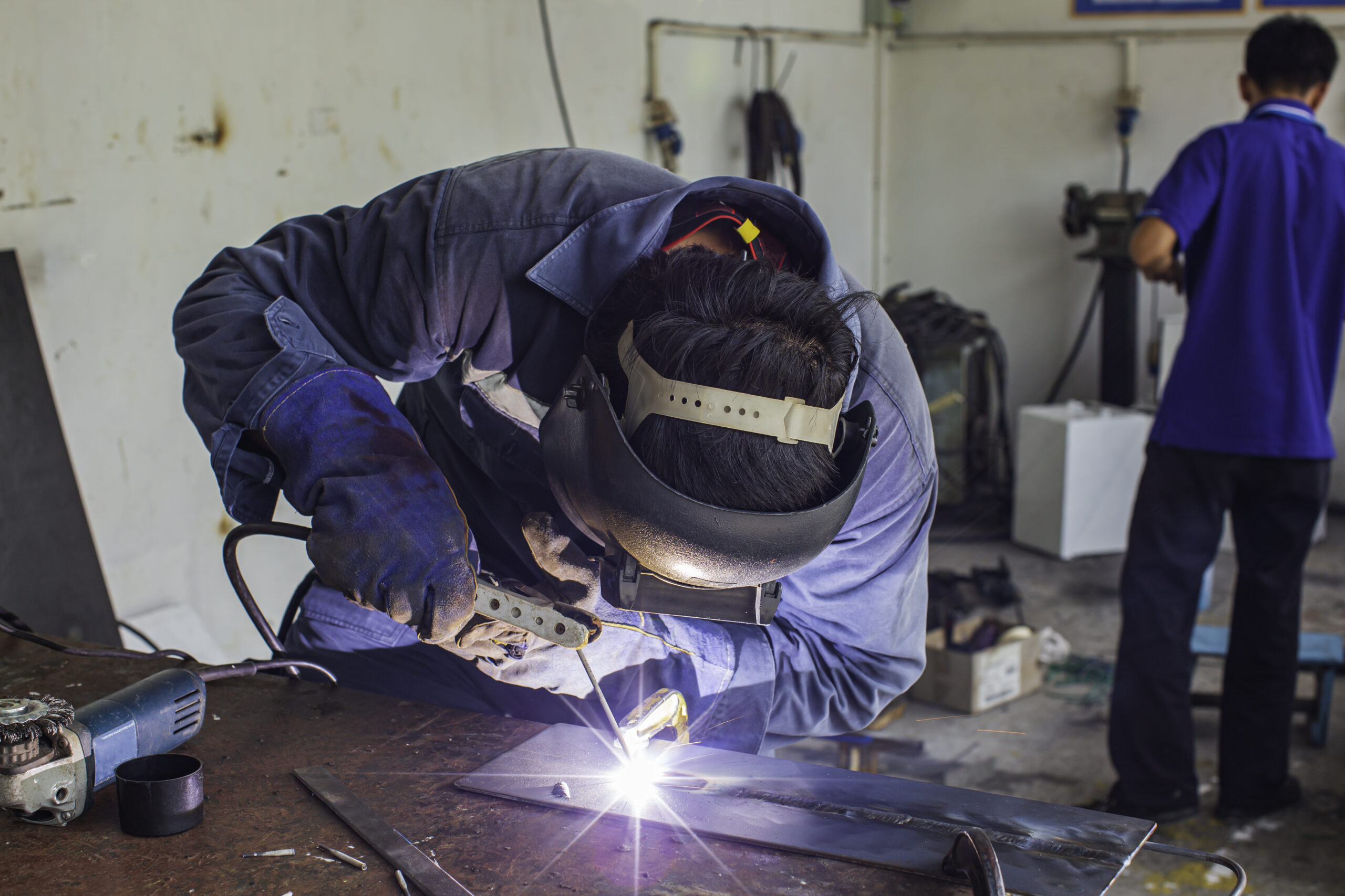 Welding male worker metal is part in machinery repair garage