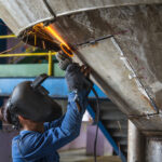 Worker grinding repair stainless silo bottom tank